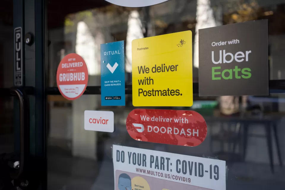 Close-up of restaurant window with various food delivery company stickers